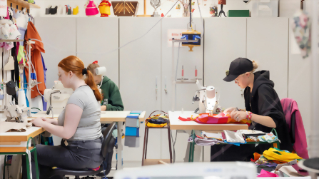 Auszubildende arbeiten an Nähmaschinen und verarbeiten Stoffe im textilen Ausbildungsbereich des Berufsbildungswerks Hettstedt.
