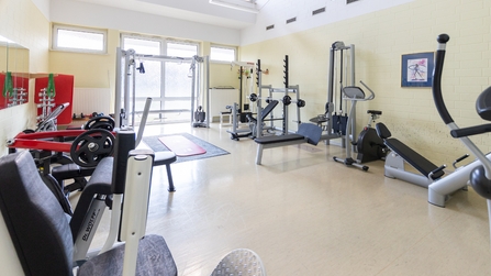 Menschenleerer Trainingsraum mit Fitness- und Kraftgeräten zur sportlichen Förderung