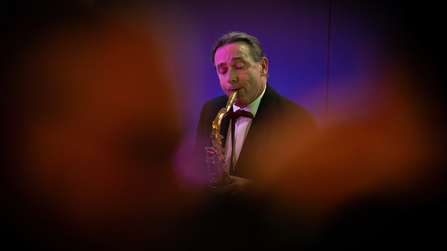 Musiker spielt Saxofon bei einer Veranstaltung im stimmungsvollen Bühnenlicht.