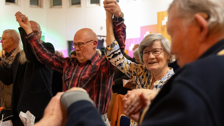 Gäste feiern, nehmen sich bei den Händen und heben die Arme hoch