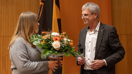 Schulleiter der Berufsschule der KBBW übergibt Blumenstrauß an Schülerin