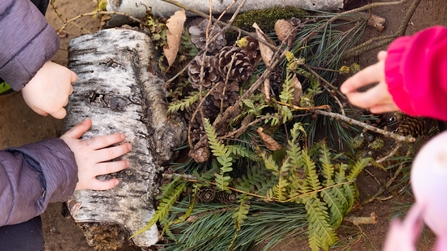 Kinderhände fügen Naturmaterialien zu einer Landschaft zusammen